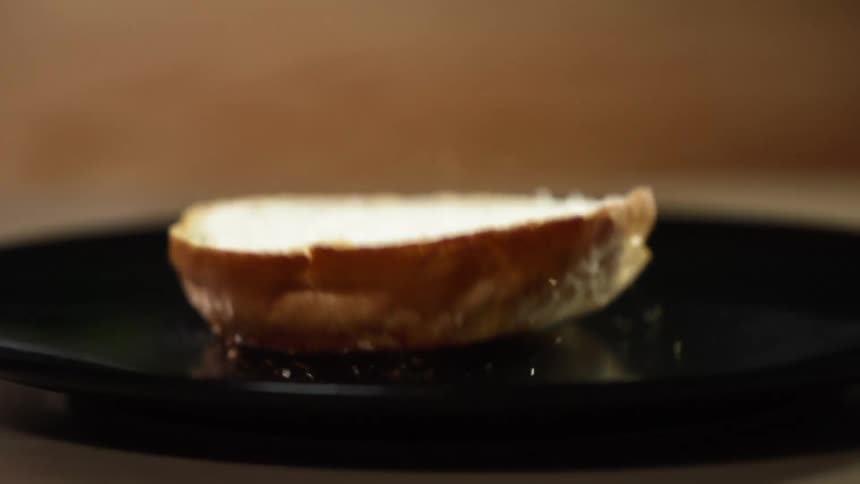 Half burger bun falls onto a black pan