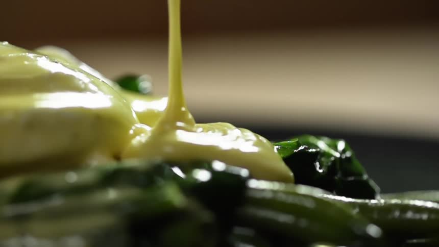 Mayonnaise being served over cooked green vegetables