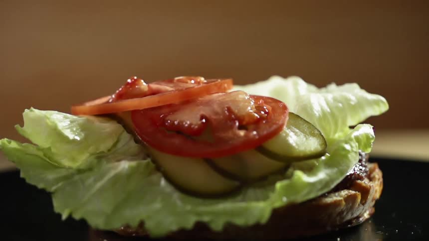 Tomato slices fall on a hamburger bun