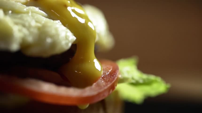 A yellow sauce runs over the outside of a hamburger