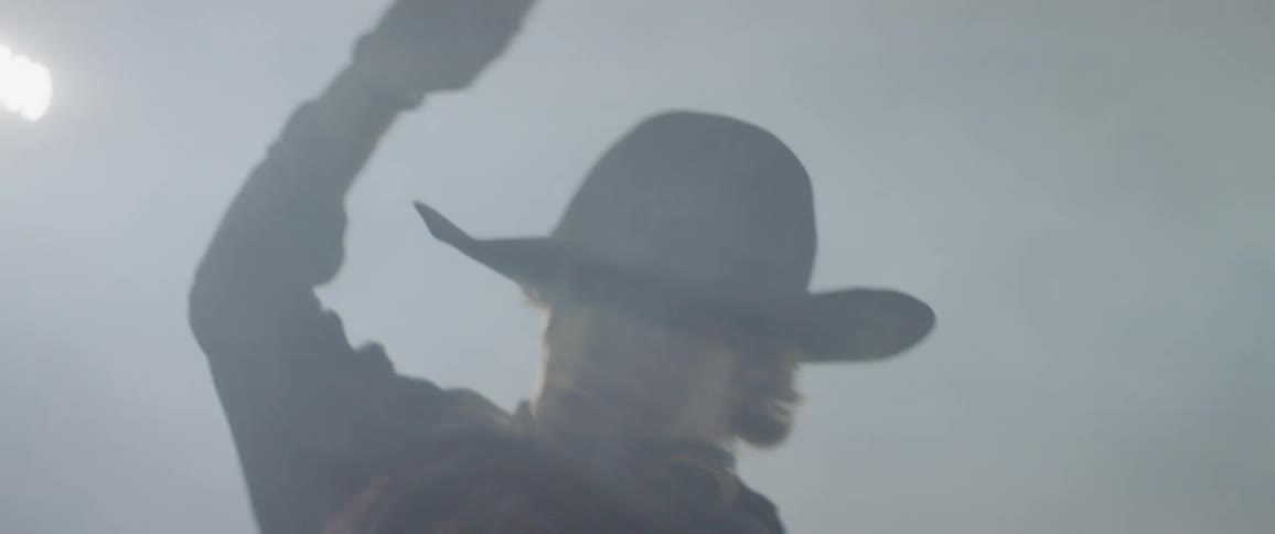 A man rides a bull in a dusty arena