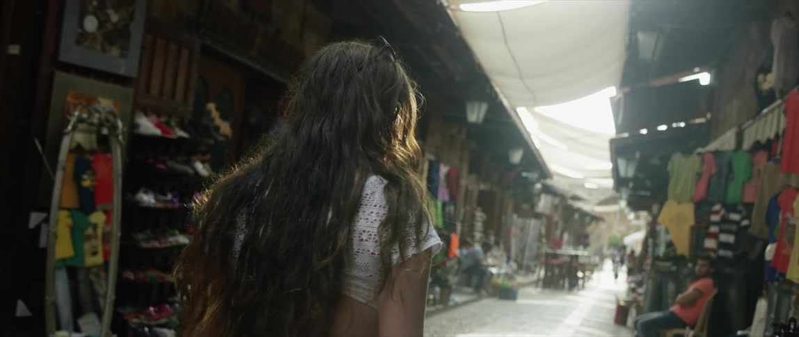 A woman is walking down an alley browsing the shops around her