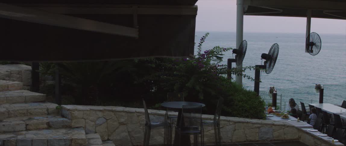 Fans blowing towards people dining next to the ocean