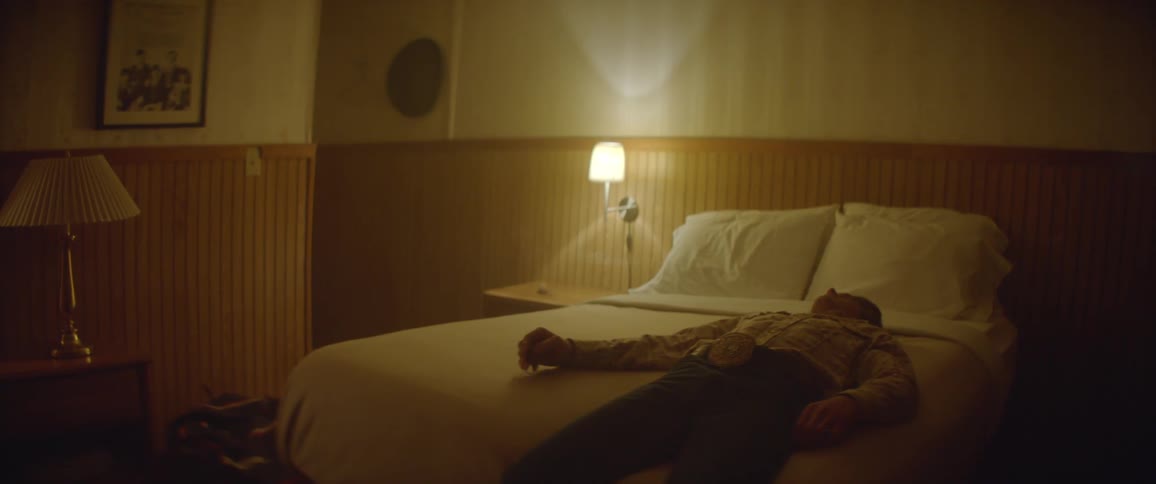 A man lays back on a hotel bed