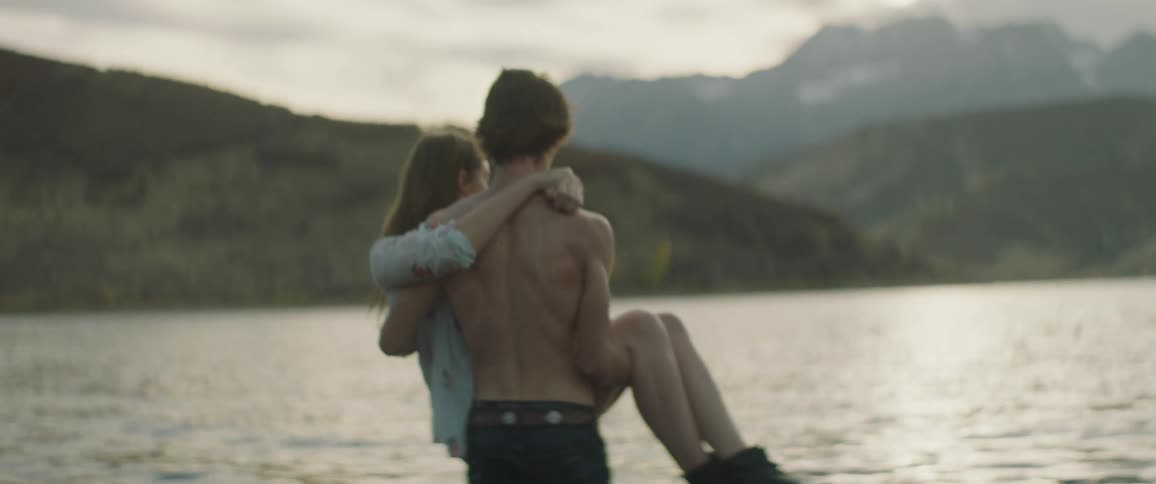 Man carrying a woman into a body of water on a cloudy day
