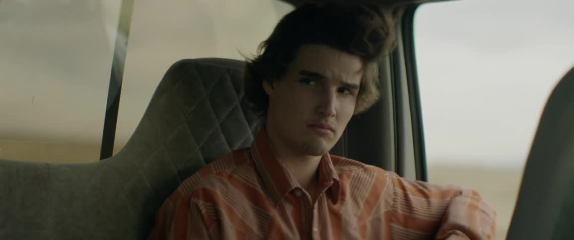 Man sits in a vehicle looking out the side window