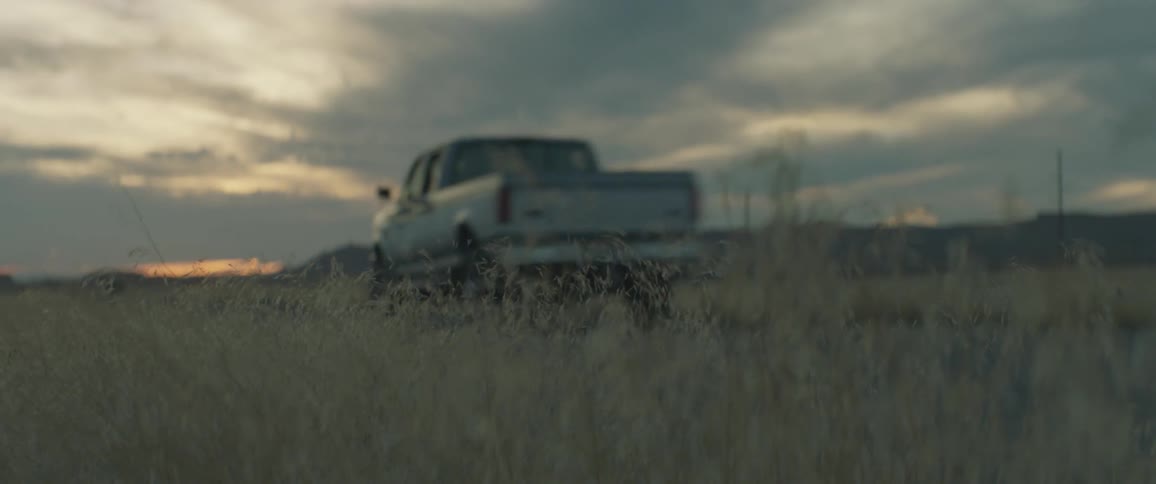 A pickup truck drives down a dirt road