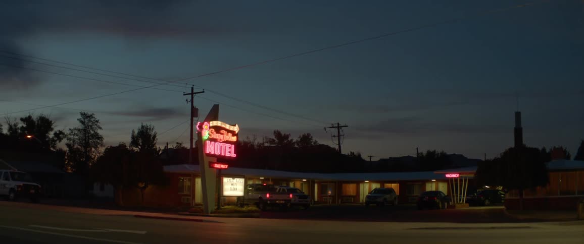 A car pulls up to a motel at night