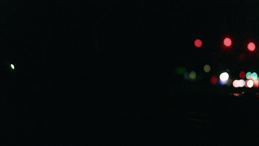 A person driving a car with lights from the city in the background