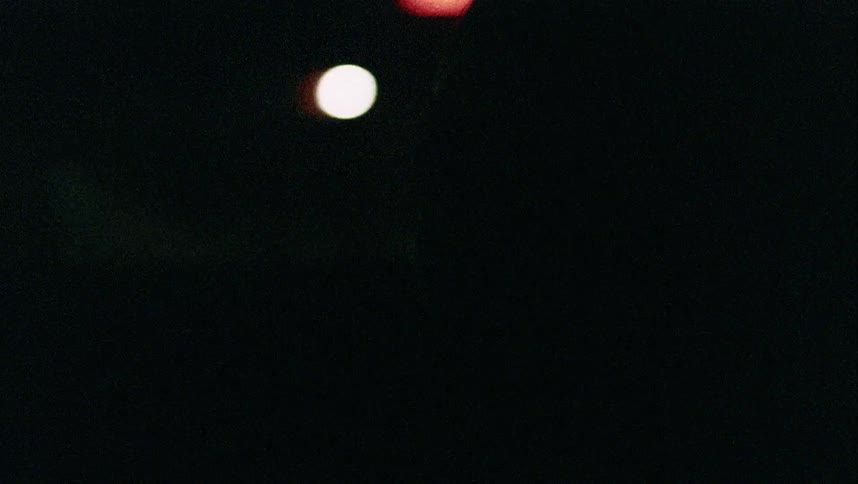 A young boy sits in a passenger seat of a moving car that is driving at nighttime