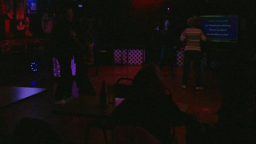 Two couples dance as singer sings in dark club