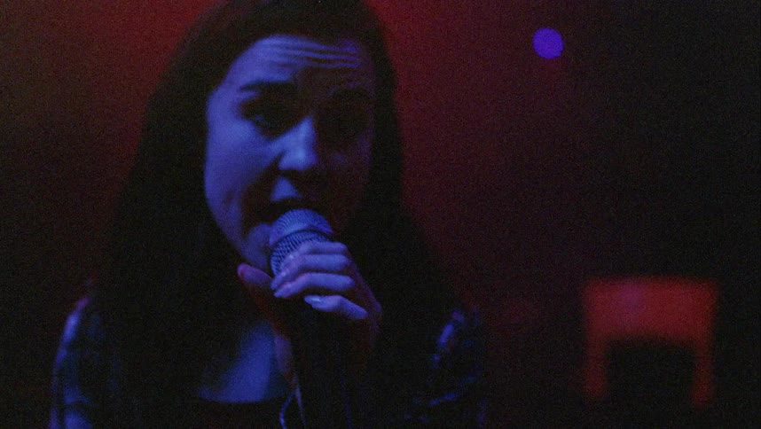 A young woman singing in a dark room