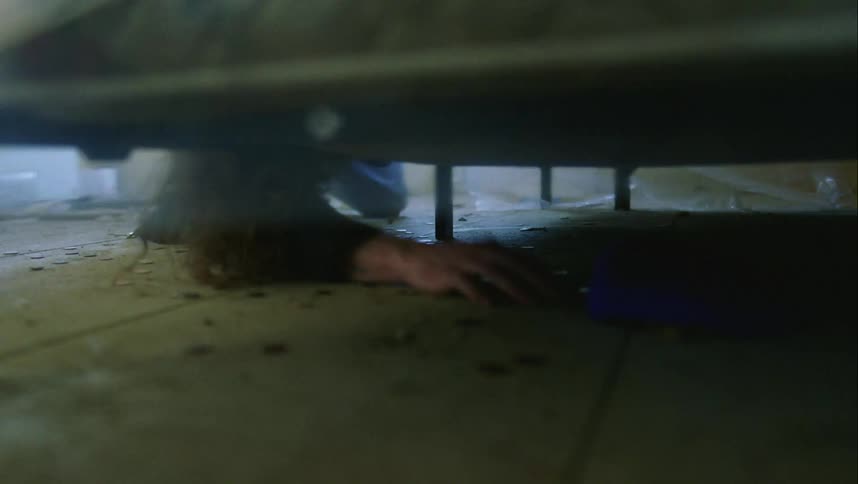 A person spills a can of coins and takes a hat from under a couch