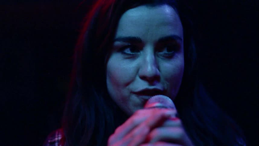 A woman with a microphone singing with lights in the background