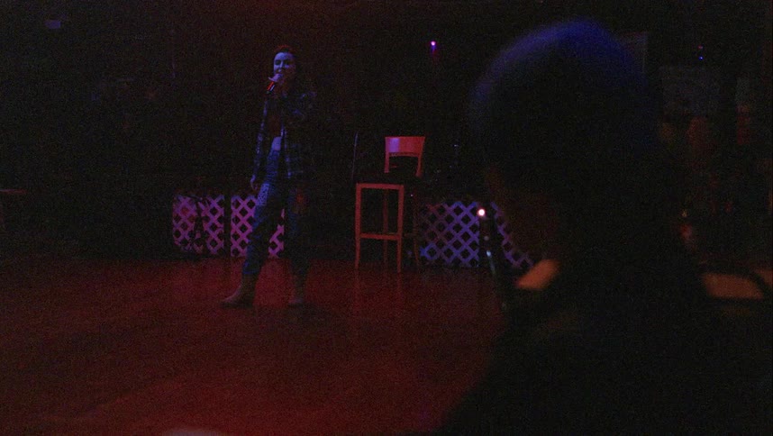 A woman with a microphone dancing and singing with people in the foreground dancing