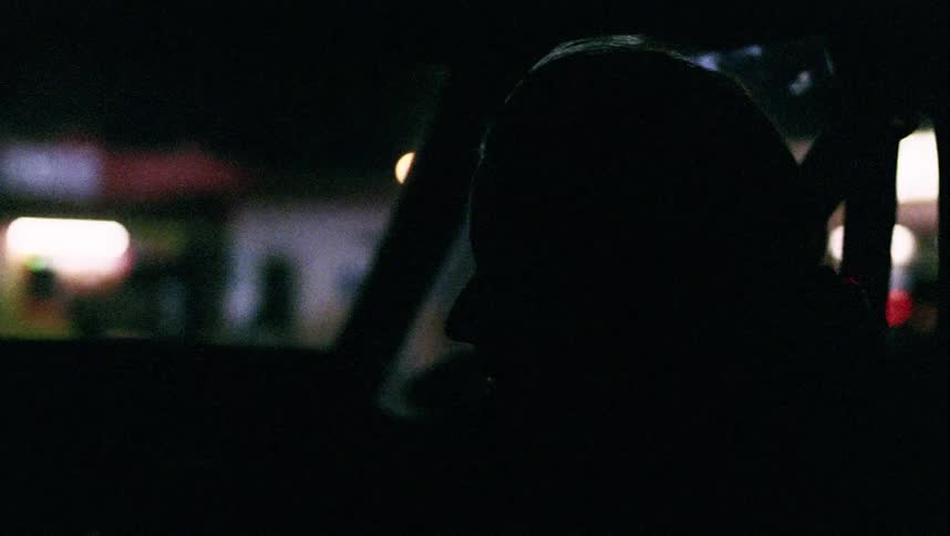 A person in a car with the city and lights outside the window