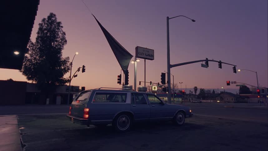 A station wagon with two people in it pulls up to a gas station and stops