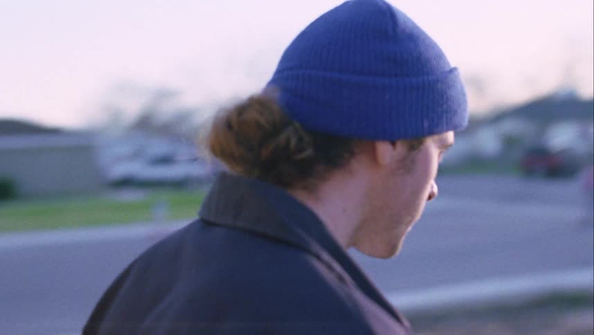 A man turns away from the front door of a house and walks away towards the road