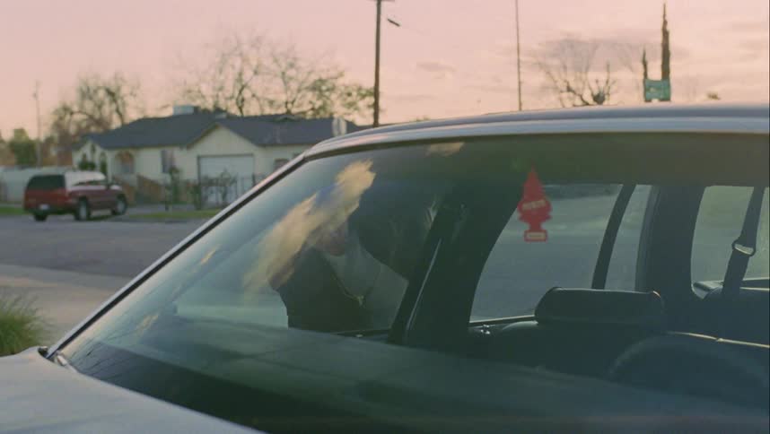 A man walks over and looks in the car