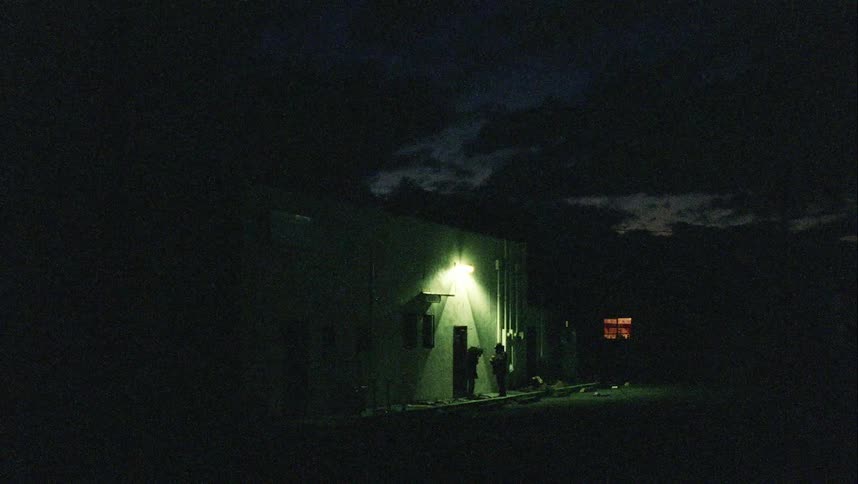 Two people interact outside the building at night