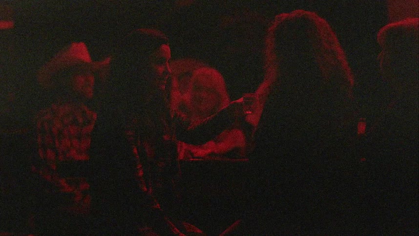 Friends drink shots in the bar inside a night club under red light