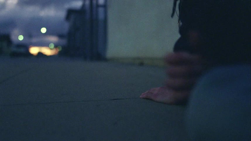 A man laying down on a pavement in the city waking up standing and walking