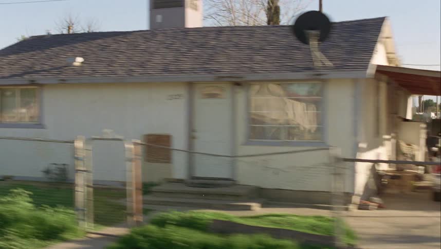 Person gets into car in neighborhood of mostly one story houses with chain link fences