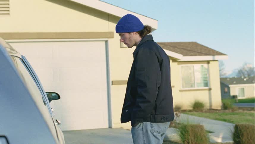 A man walks and stops to look into a car