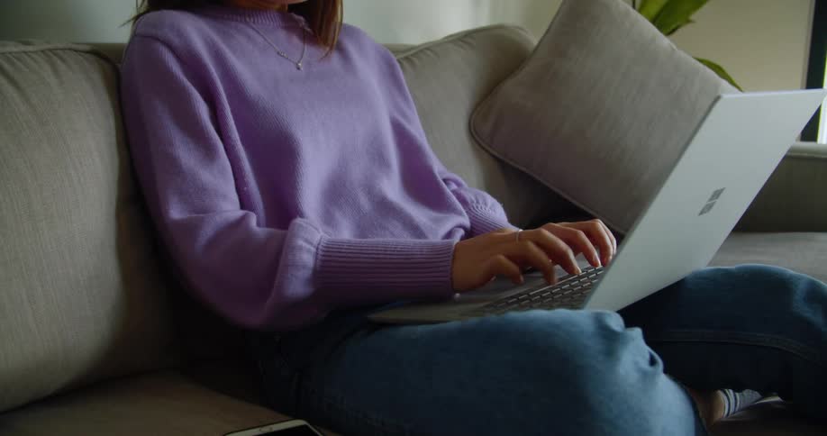 A woman is at home typing on her keyboard