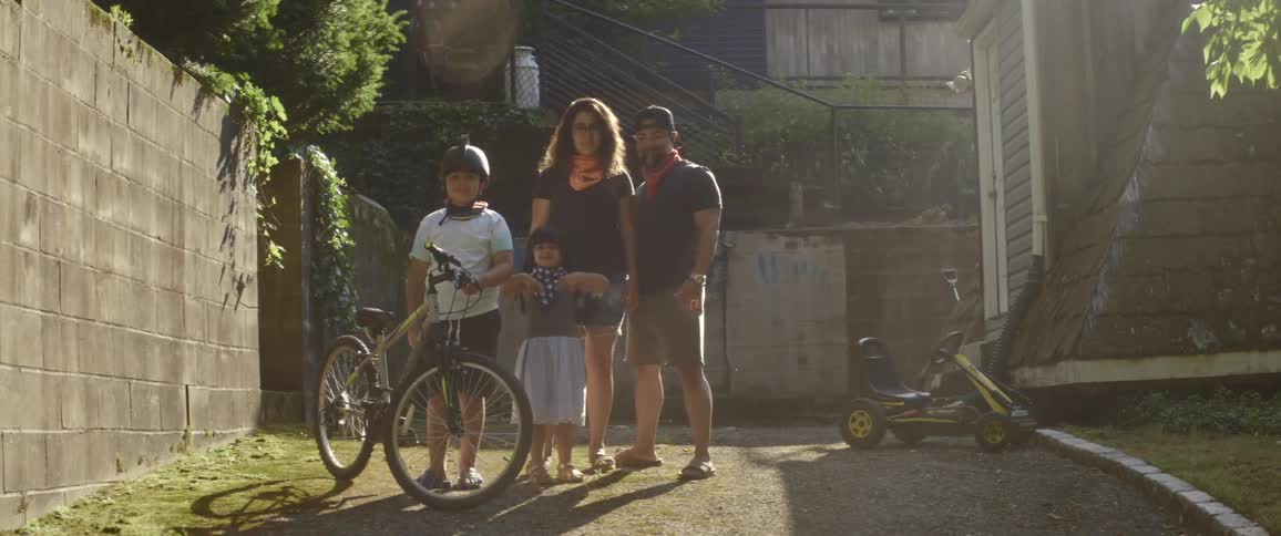 A man woman girl and boy with a bike standing in a driveway
