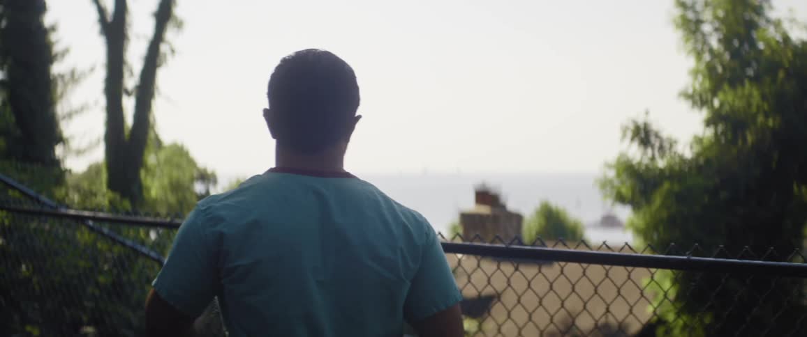 A man removes his mask and walks over to the fence
