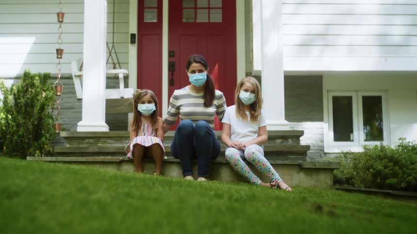 A woman and children sit on the stoop by the house