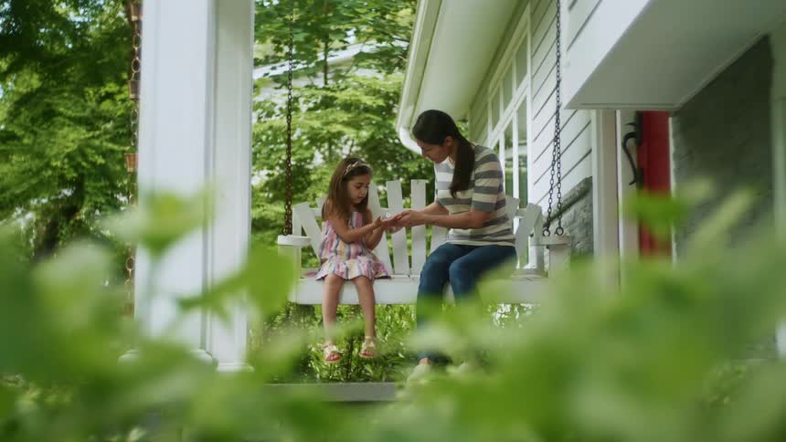 A mother and daughter sit out on the porch