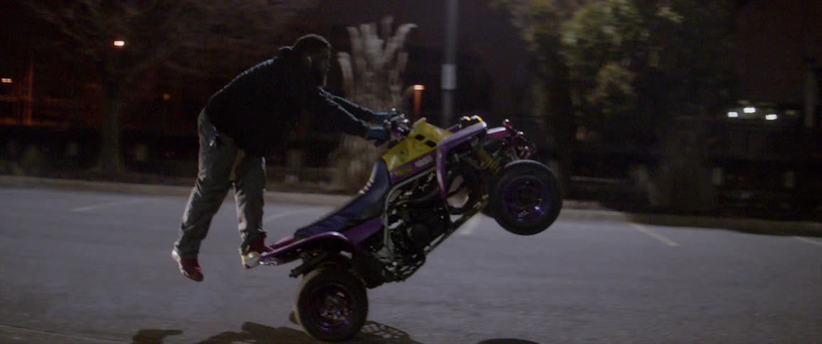 A man rides a four wheeler in a parking lot