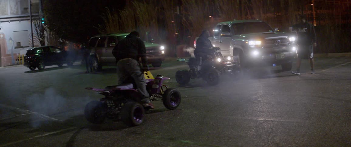 A man does donuts on the street while riding an atv