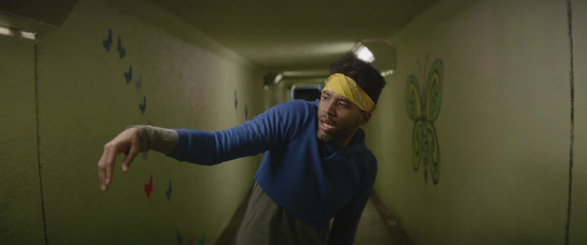 Man dances in a dimly lit hallway with butterfly decals on the walls