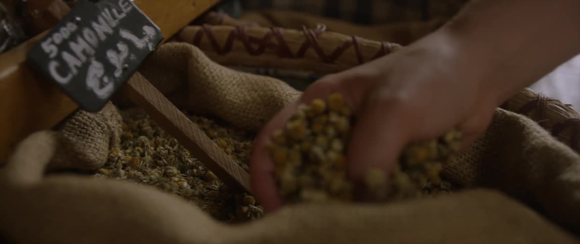 A woman scooping grain from a burlap bag