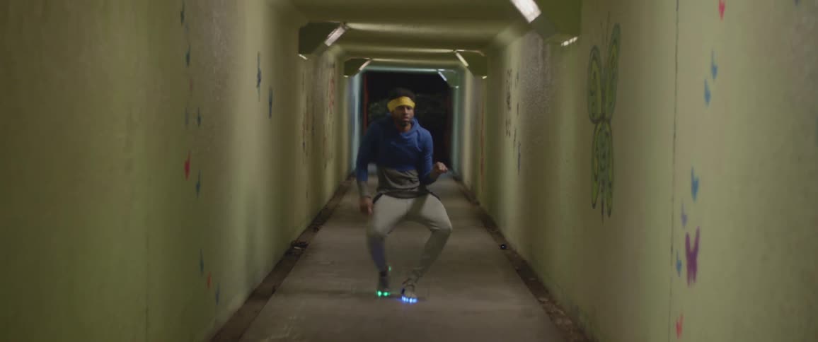 Man dancing and grooving while standing in a hallway with lighted shoe soles