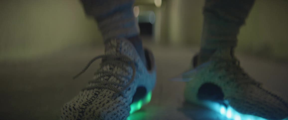 Person wearing light up shoes dances in a dim hallway