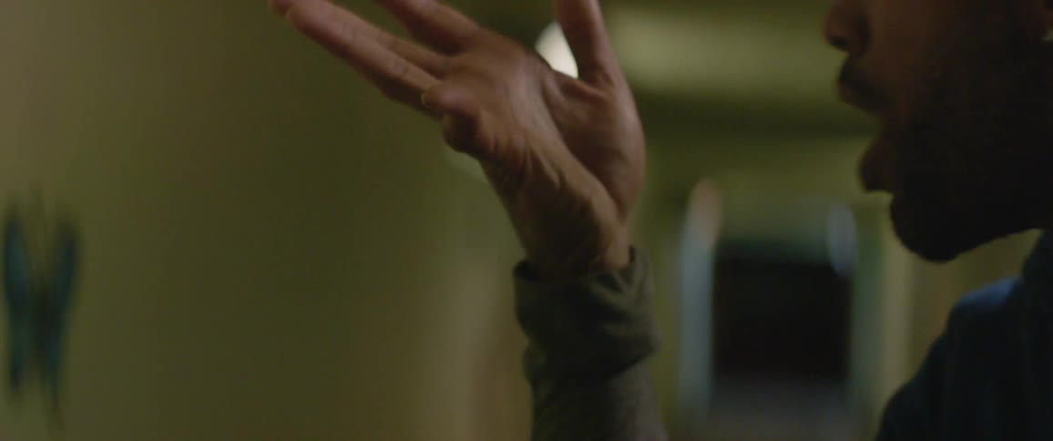 A man gestures with his hand in a hallway