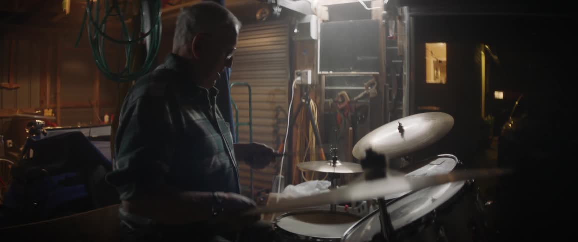 A man plays drums in a garage