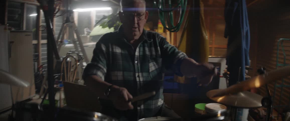 Elderly man playing drums in a garage
