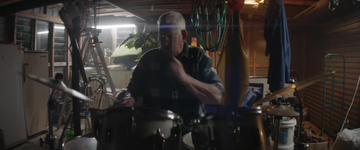 A man plays drums in a garage