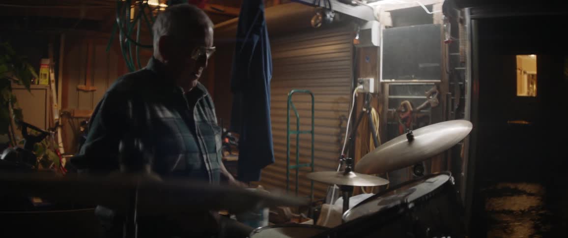 A man plays drums in a garage