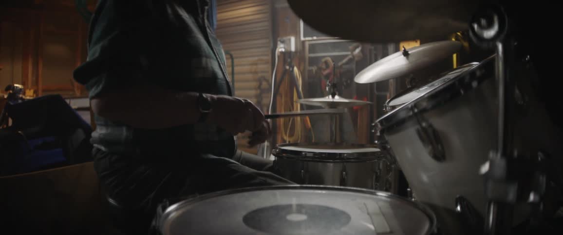 A man plays drums in a garage