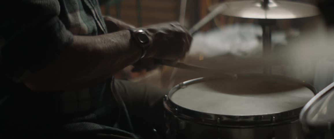 A man plays drums in a garage