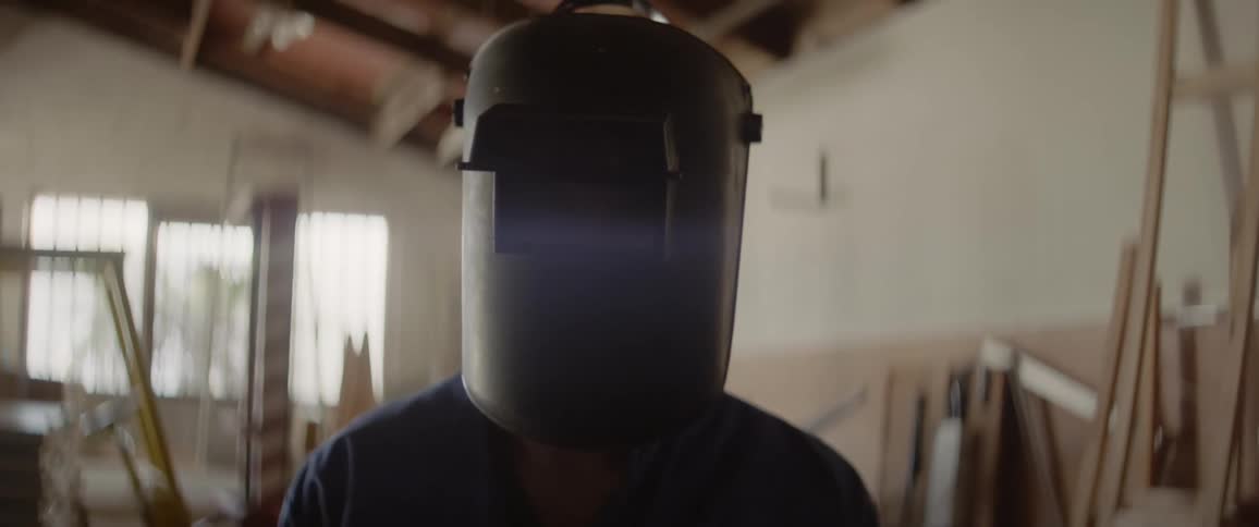 A person wears a welding mask in a workshop
