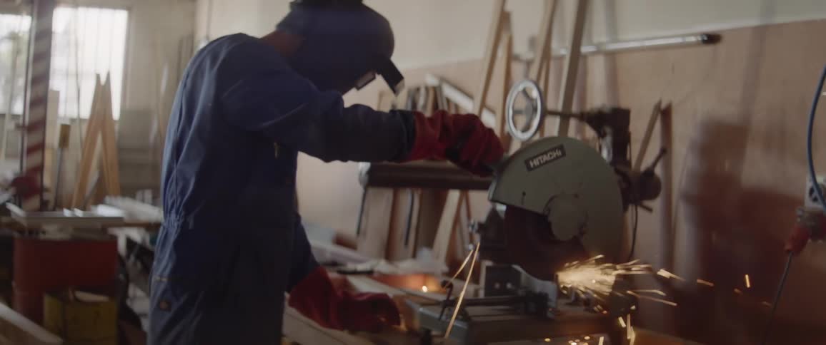 A man is using a circular saw as he works at a workbench inside during the day
