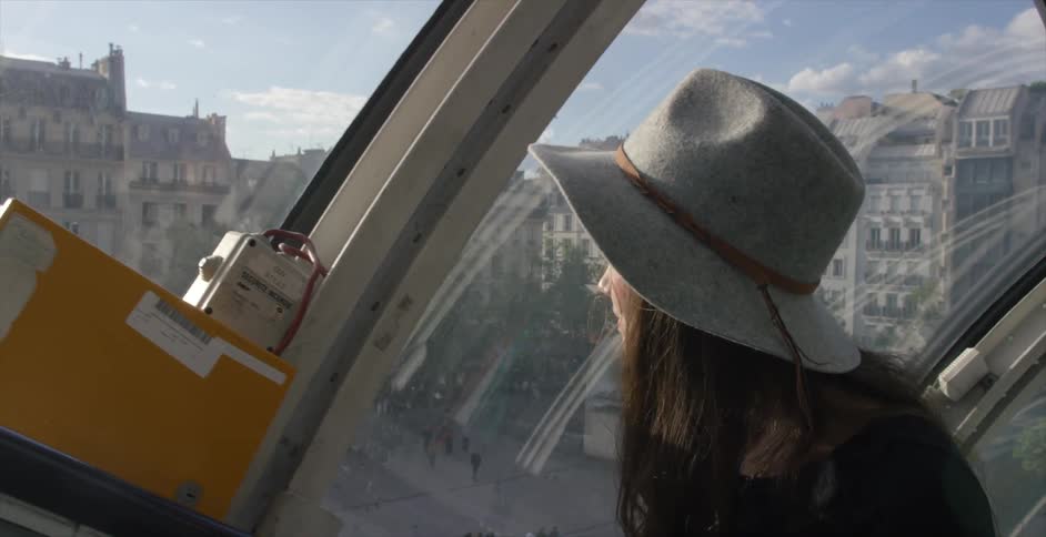 A woman moving as she looks out of a window viewing a city