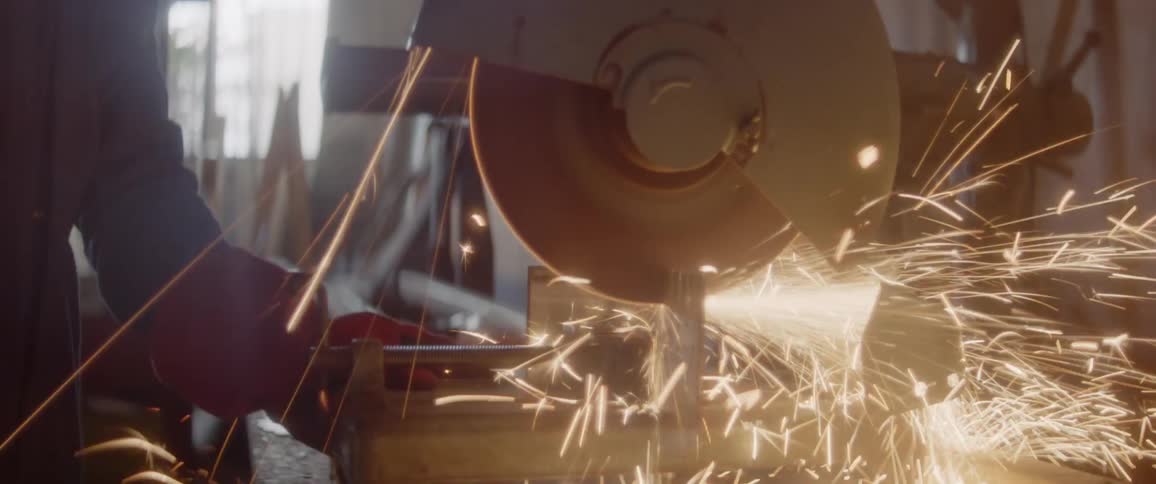 Sparks are flying from a circular saw as it is used in a shop during the day